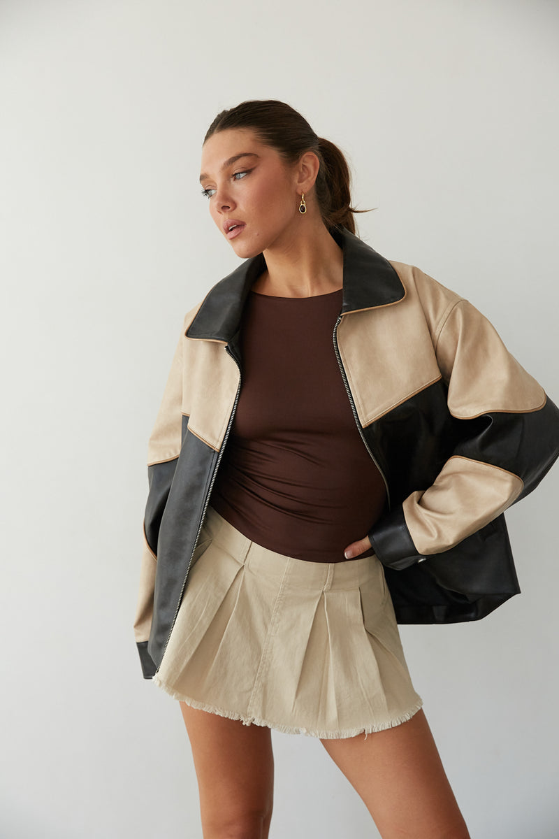 Girl in a two-tone leather jacket, brown top, and pleated mini skirt from American Threads, a cute fall look.