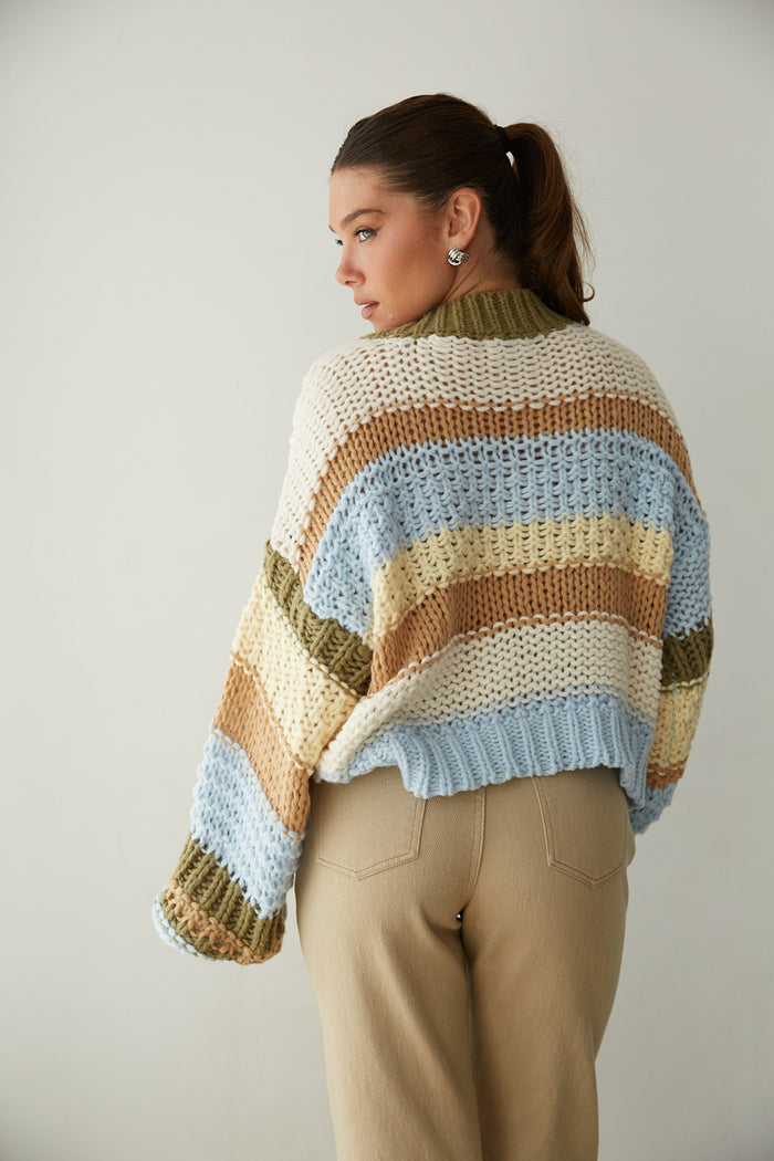 A woman in a striped knit sweater and beige pants from American Threads, showcasing cute fall clothing style.